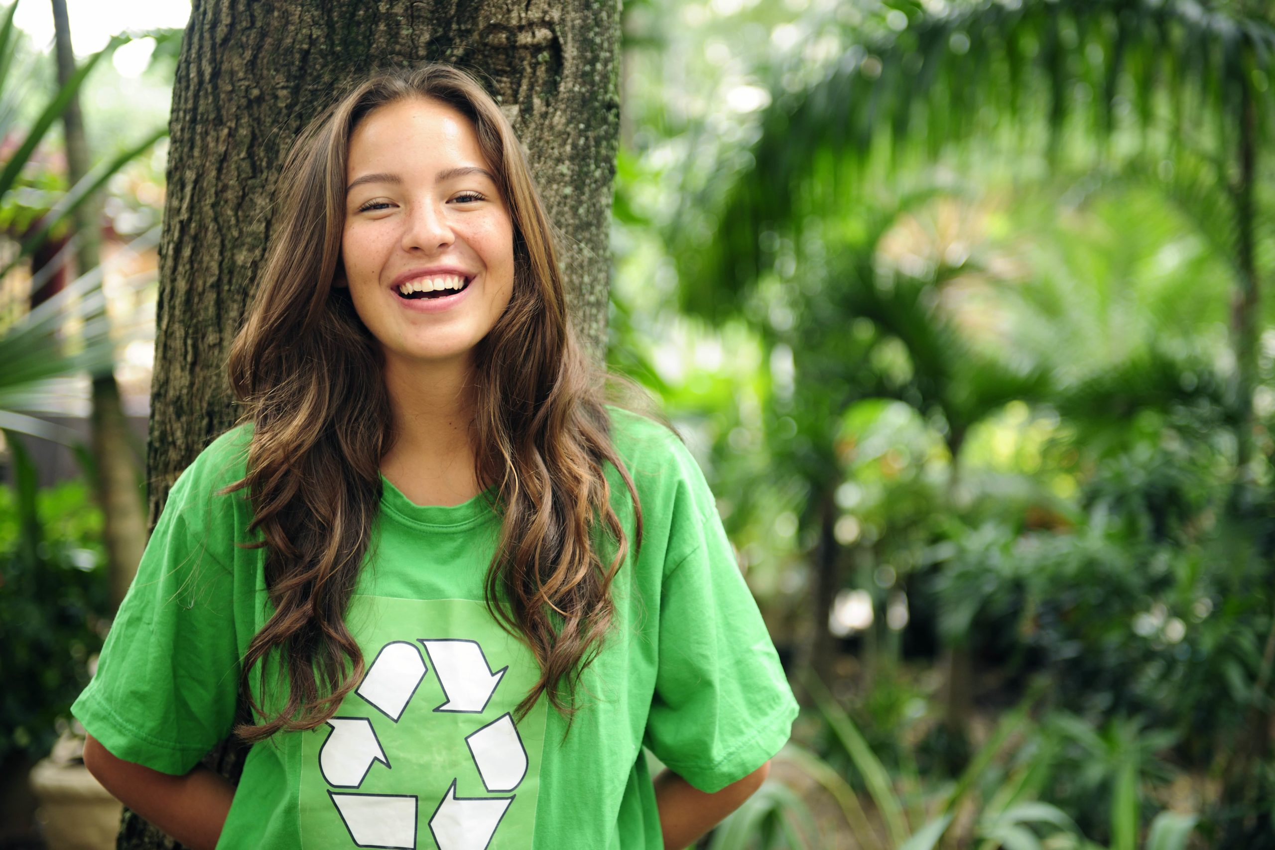teen girl laughing in forest with green recycle shirt