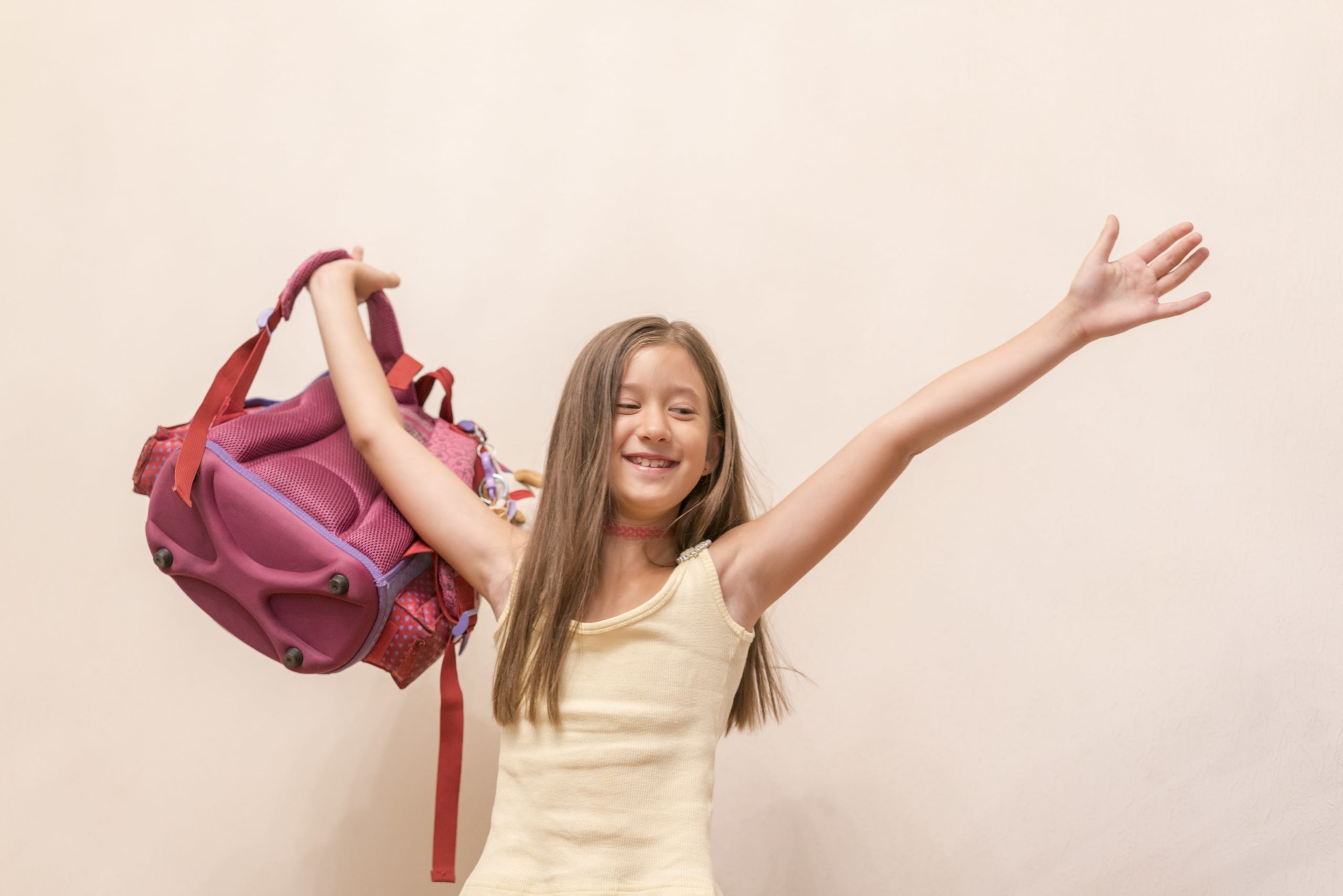 happy girl celebrating with arms up and backpack